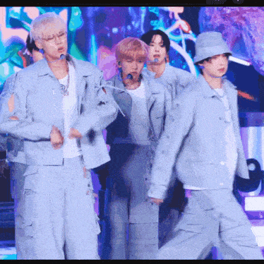 a group of young men are standing on a stage wearing blue jackets and hats