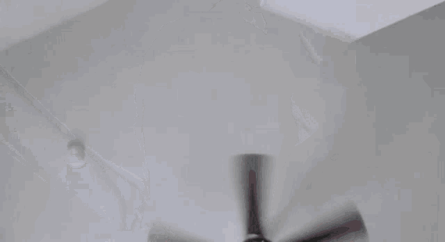 a man stands in front of a ceiling fan that is spinning