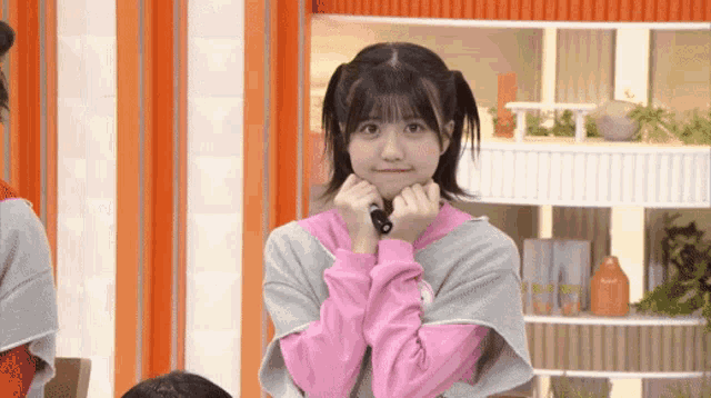 a young girl in a pink sweater is making a funny face .
