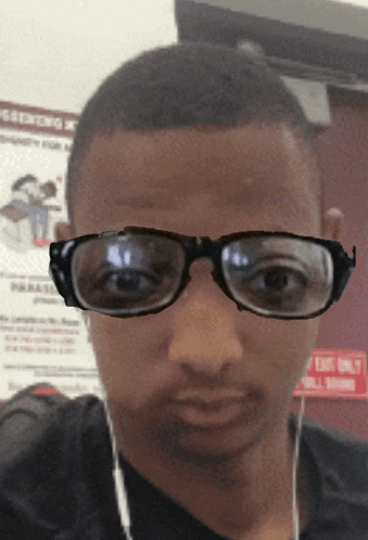 a man wearing glasses is standing in front of an exit only sign