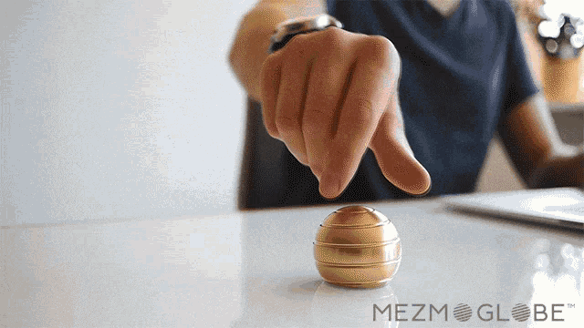a man is playing with a gold globe that says mezm globe on it