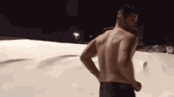 a shirtless man is standing in the snow .