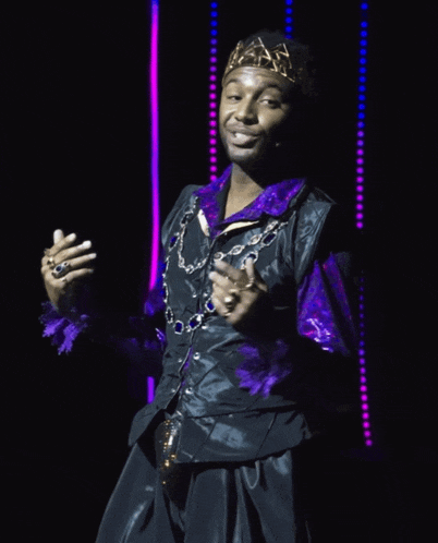 a man with a crown on his head is wearing a purple shirt