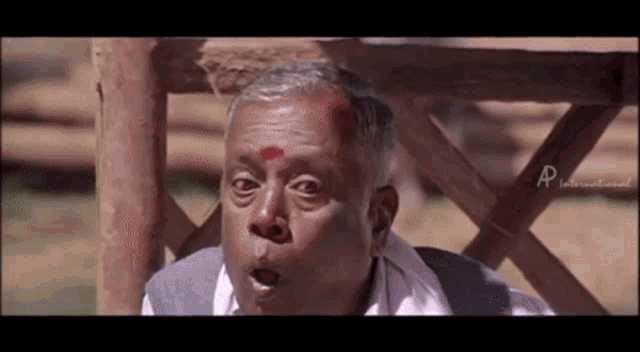 a man with a red dot on his forehead is making a funny face .