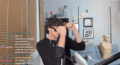 a man wearing headphones is looking through a pair of binoculars in front of a couch with a mannequin in the background