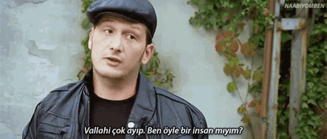 a man wearing a hat and a leather jacket says vallahi çok ayip