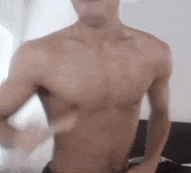 a shirtless man is dancing in a bedroom .