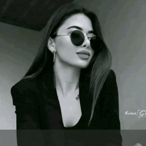 a black and white photo of a woman wearing sunglasses and a jacket