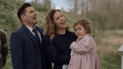 a man and woman holding a little girl in a pink coat