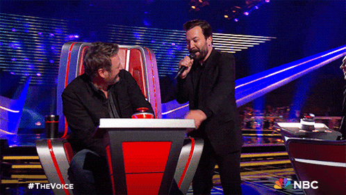 two men sitting at a table with a nbc logo on the bottom
