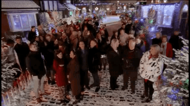 a group of people standing in front of a christmas tree in the snow