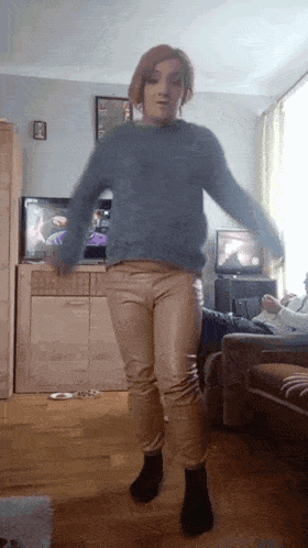 a woman in a blue sweater and tan pants is dancing