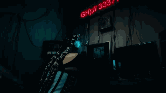 a person is sitting in front of a neon sign that says 3hx / 33 / 7