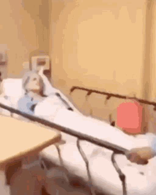 a person is laying in a hospital bed in a room with a table .