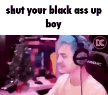 a man wearing headphones is sitting in front of a computer screen and says `` shut your black ass up boy '' .