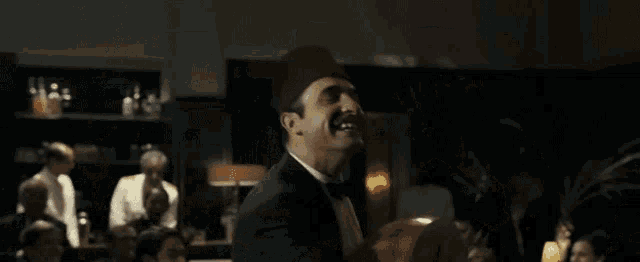 a man in a tuxedo is playing a guitar in front of a crowd