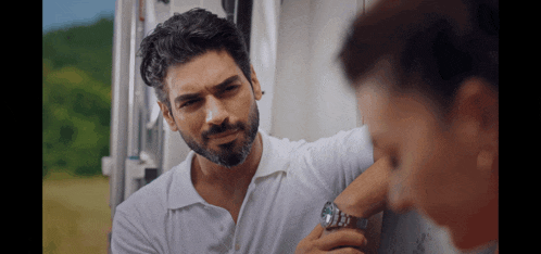 a man with a beard is leaning against a wall