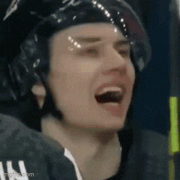 a close up of a hockey player wearing a helmet with his mouth open .