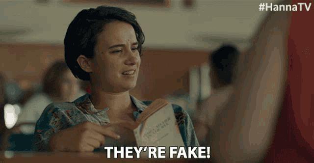 a woman holding a book with the words they 're fake below her