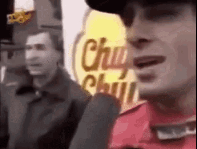 a man is talking into a microphone in front of a chupa chips sign .