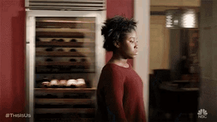 a woman is standing in front of a wine fridge in a kitchen .