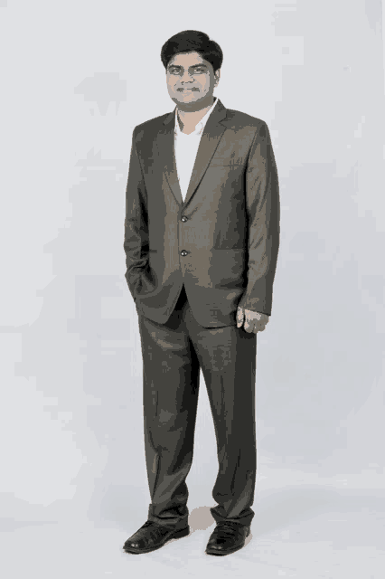 a man in a grey suit and white shirt stands with his hands in his pockets