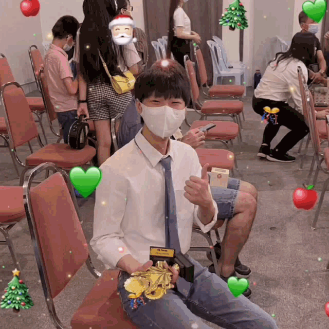a man wearing a face mask is sitting in a chair with a christmas tree in the background