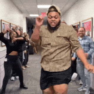 a man with a beard is dancing in a hallway with other people