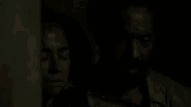 a man and a woman are standing in a dark room .