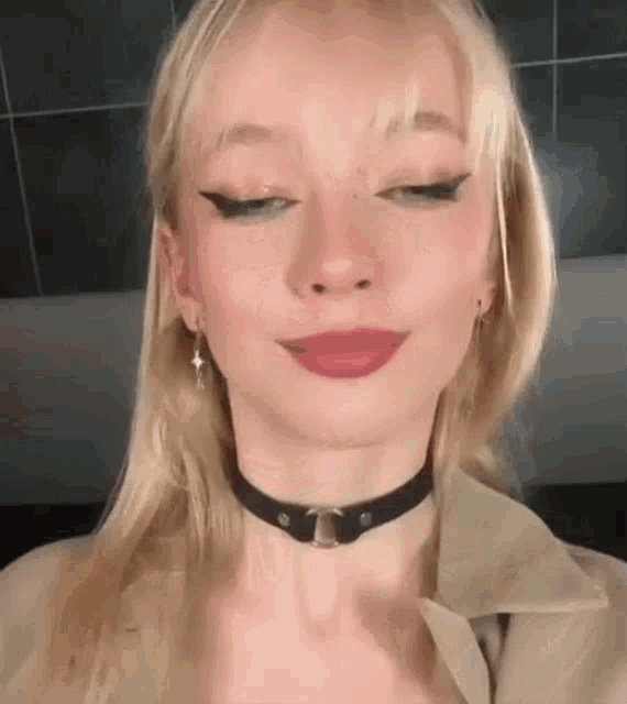 a woman wearing a choker and earrings is making a face .