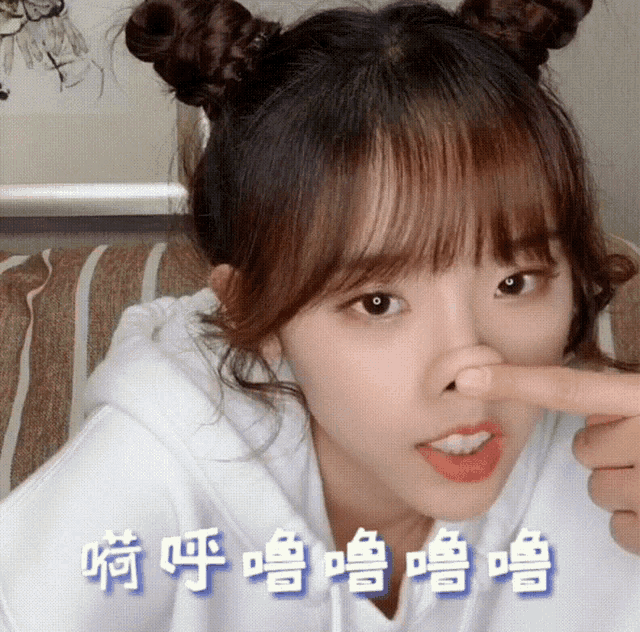 a girl with two buns on her head is holding her nose