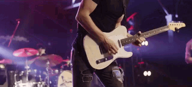 a man in a black shirt is playing a white guitar on stage