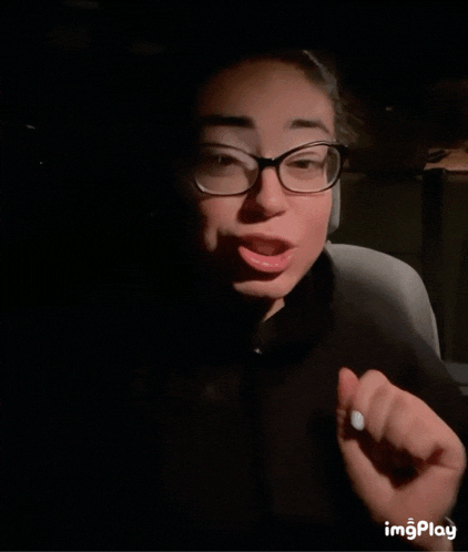 a woman wearing glasses is making a funny face in a dark room with the words imgplay below her
