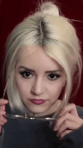 a woman with blonde hair is holding glasses in front of her face