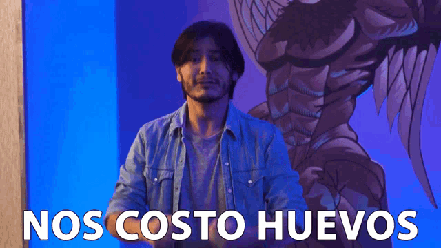 a man stands in front of a blue wall with the words nos costo huevos written on it
