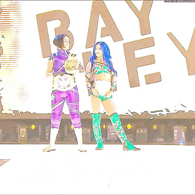 two female wrestlers are standing in front of a large letter b