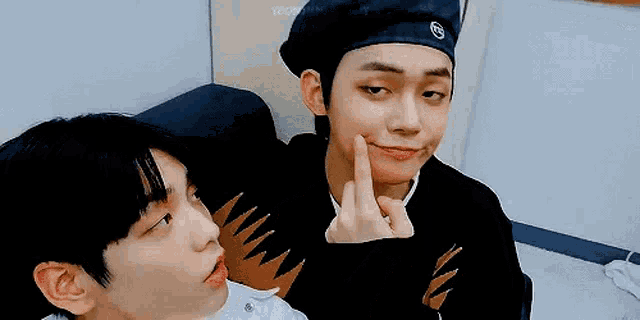 two young men are sitting next to each other and one of them is making a face .