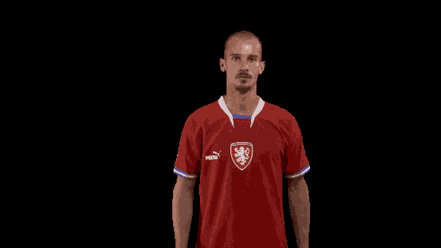 a man is wearing a red puma jersey with a lion on it