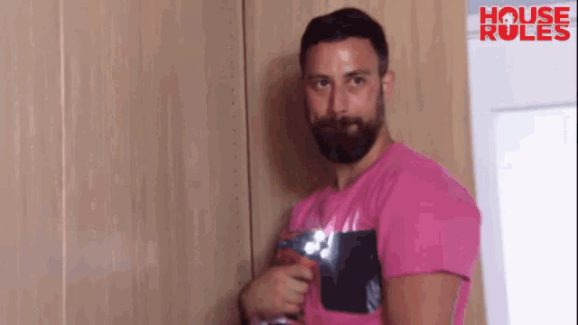 a man with a beard is wearing a pink shirt with the words house rules on the bottom