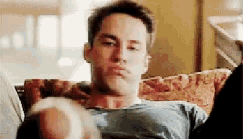 a man is sitting on a couch making a face .