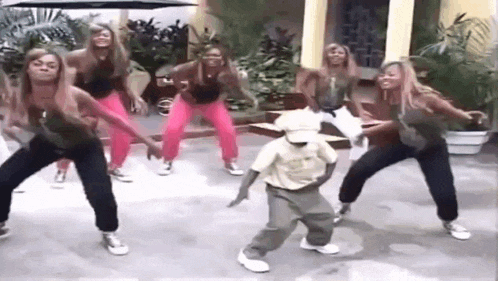 a group of women and a boy are dancing together on a street .