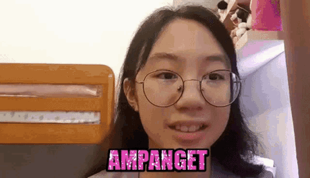 a young girl wearing glasses is smiling and standing in front of a bunk bed .