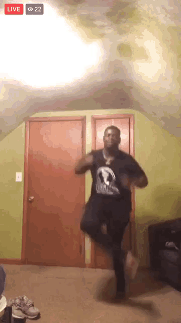 a man in a black shirt is dancing in a room with a live button