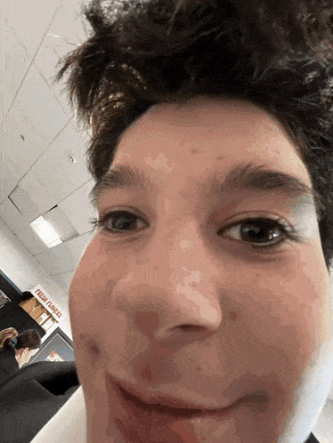 a close up of a person 's face in front of a sign that says fresh groceries
