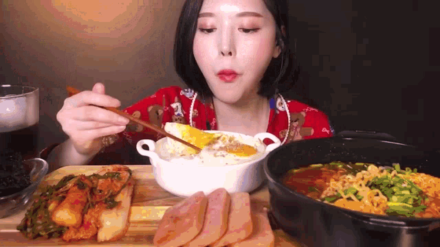 a woman is eating food with chopsticks and a bowl of food in the background