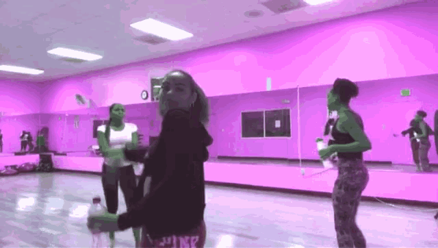 a group of women are dancing in a dance studio with purple walls .