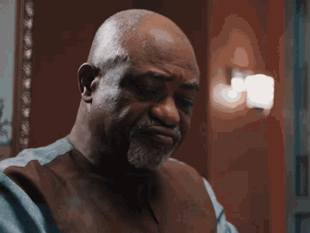a man with a beard and a brown vest is looking down
