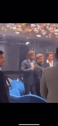 a group of men in suits are standing in a dark room .
