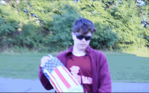 a man wearing sunglasses is holding a skateboard with an american flag design