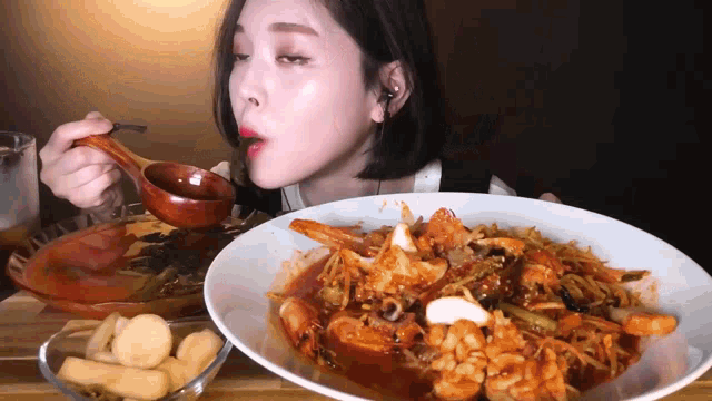 a woman is eating a large plate of food with a wooden spoon